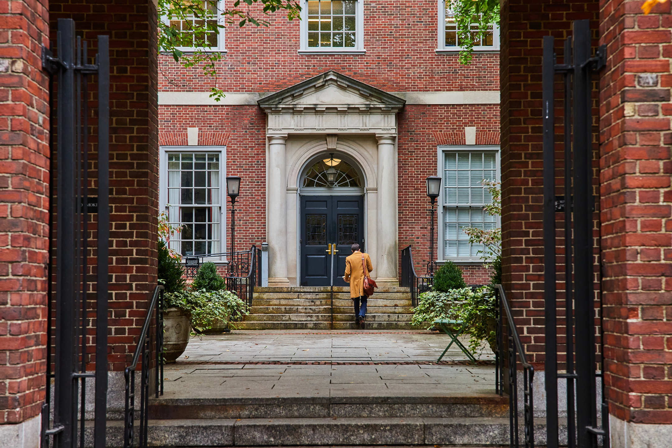 Law student walking through courtyard from brick arches in New York City straight on by Nicholas J. Klein